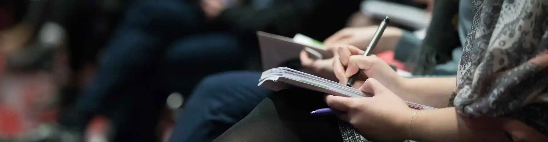 Delle persone con dei quaderni che prendono appunti