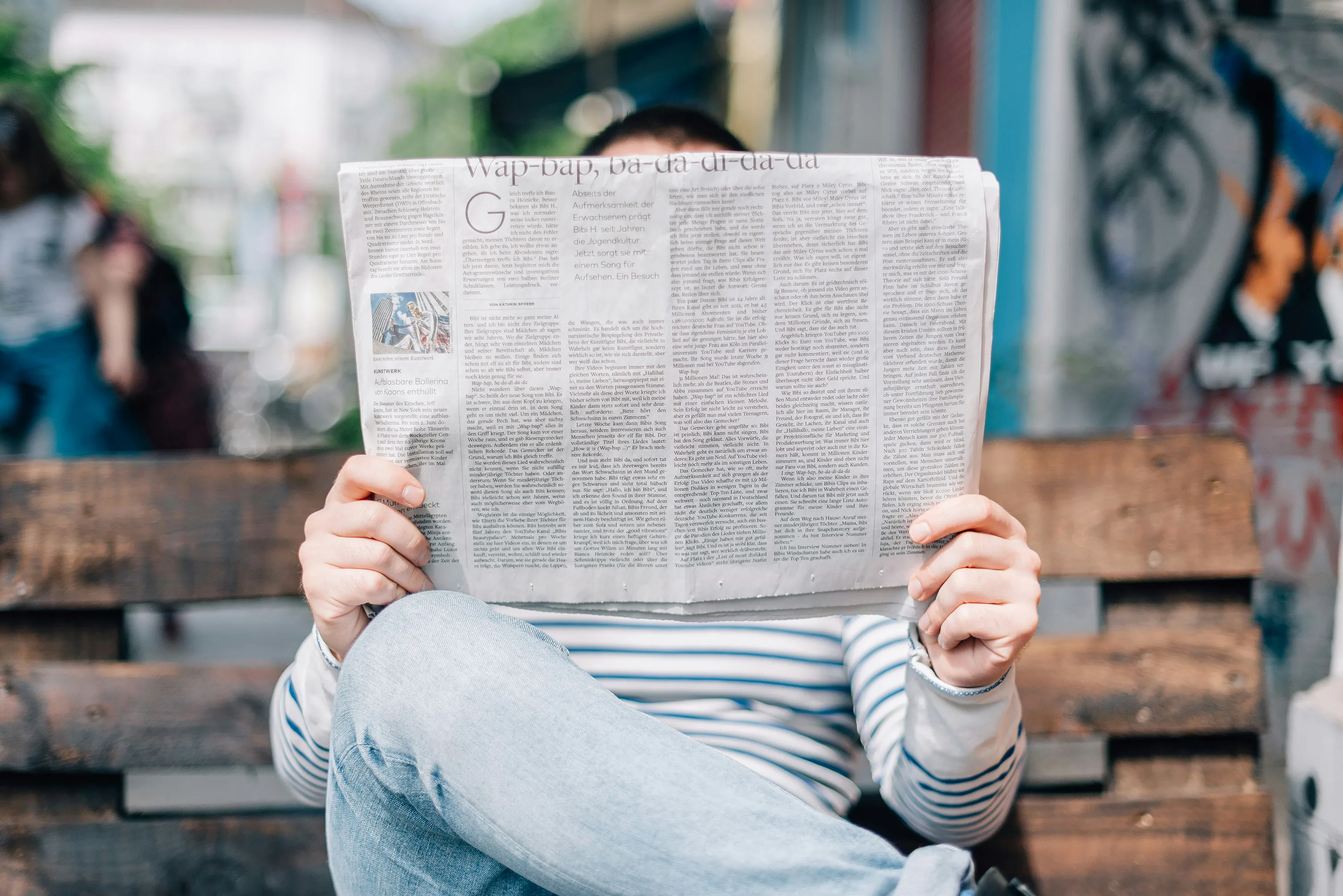 Una persona che legge un giornale seduto su una panchina