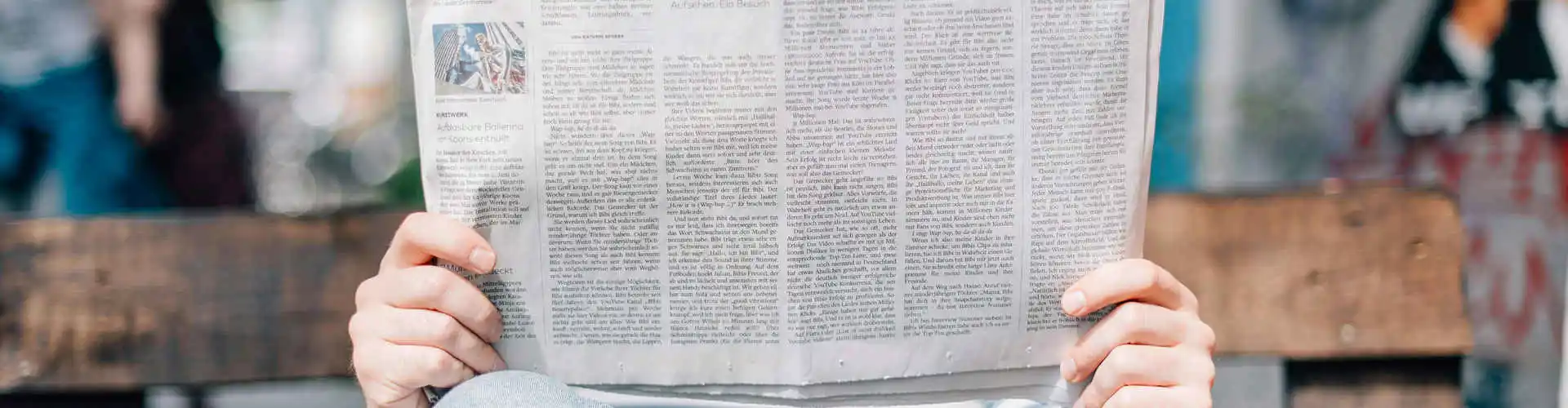 Una persona che legge un giornale seduto su una panchina